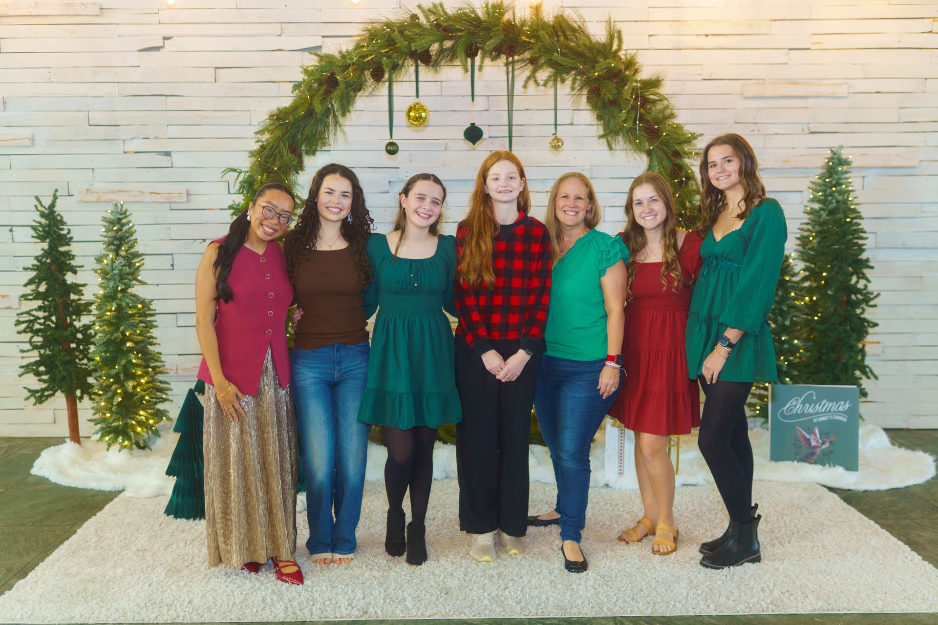 Friends posing together in front of a Christmas wreath